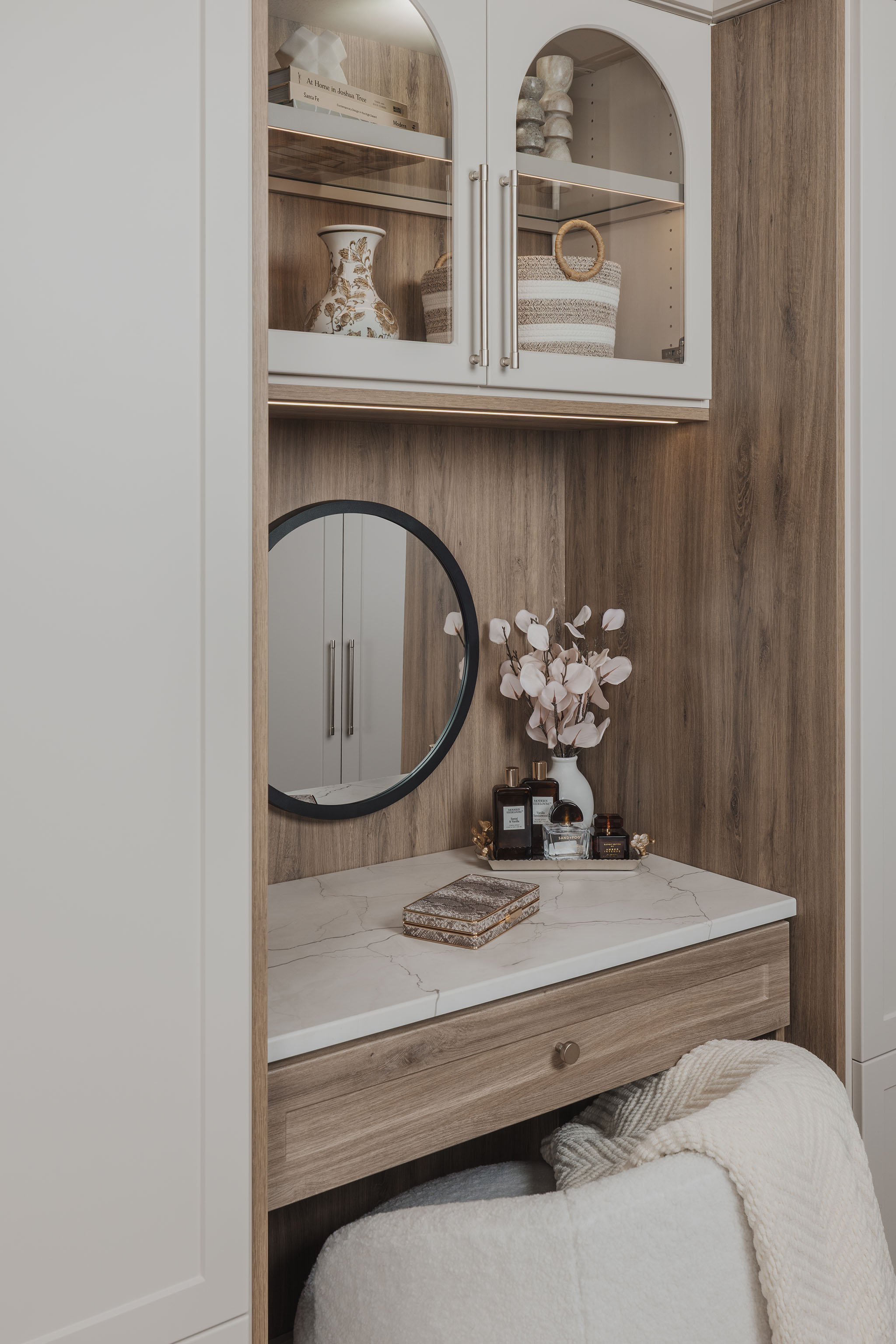 Close up of a round black framed mirror on a light wood vanity unit