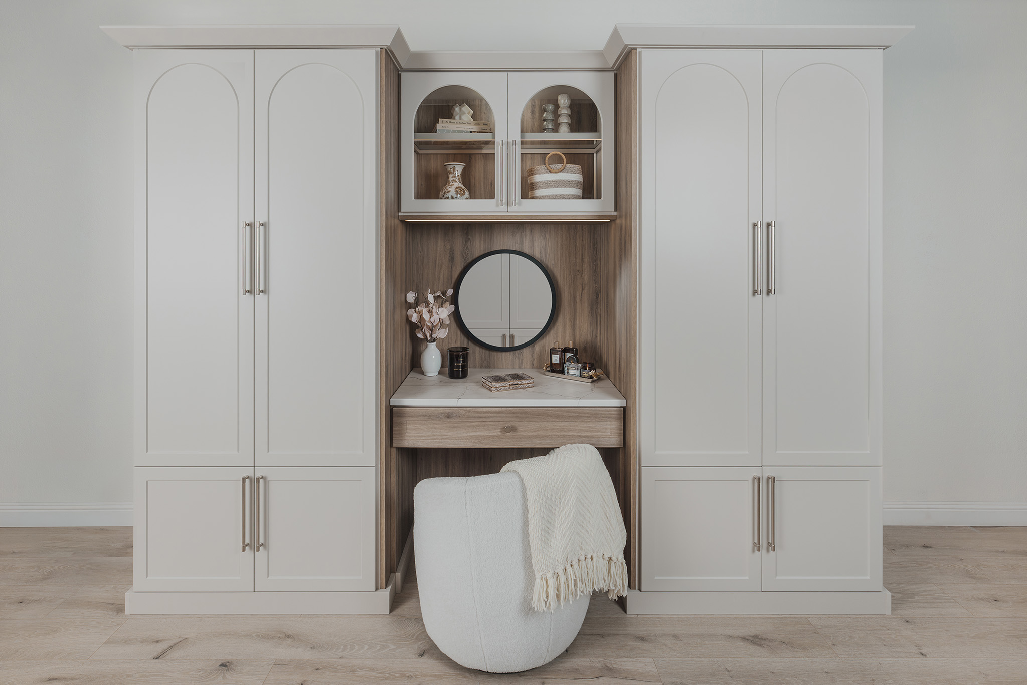 Light wood custom wardrobe system featuring open compartments and a vanity mirror