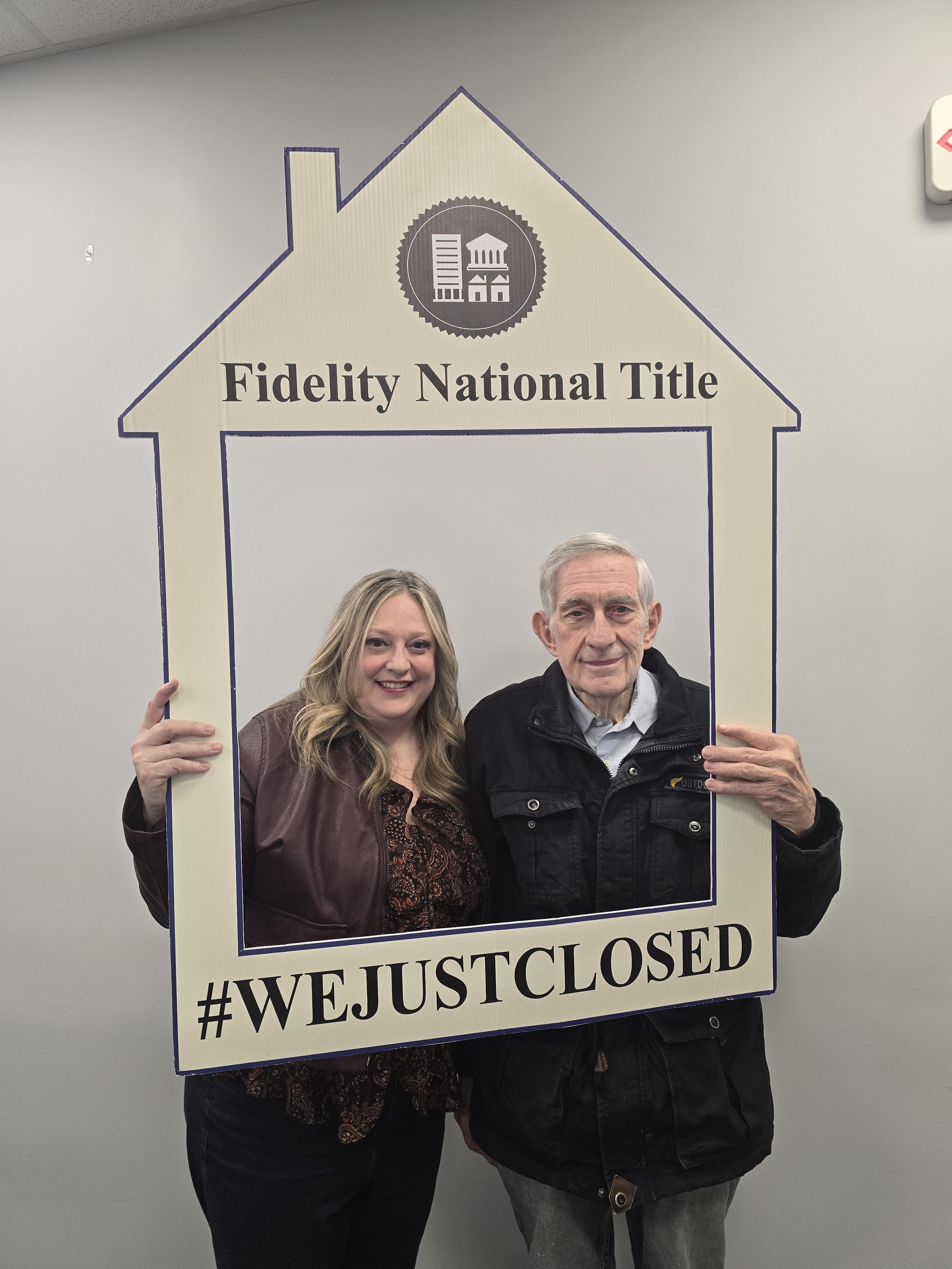 Heather and her father holding Fidelity National Title We Just Closed sign after home sale and purchase in Joliet Illinois