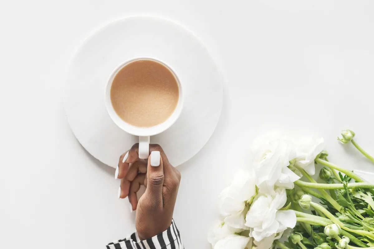 woman holding cup of coffee with nice nails