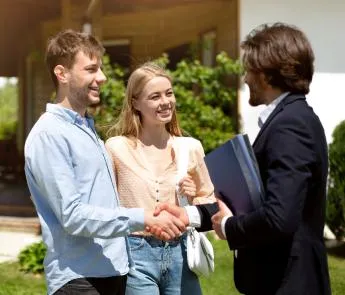 Rize Mortgage LO handing house keys to new homeowners in front of their house