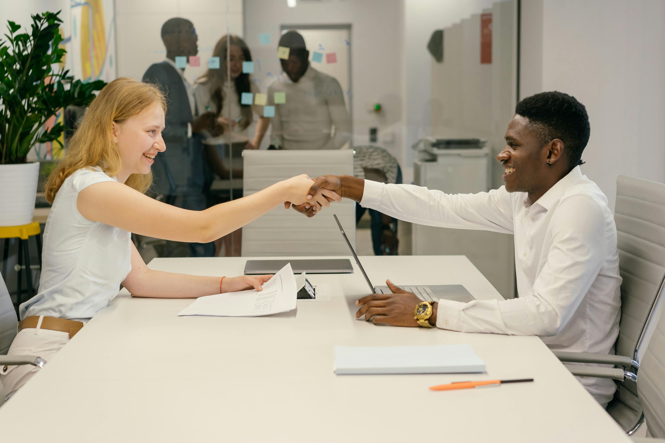 Image of two people shaking hands over a table in an office.