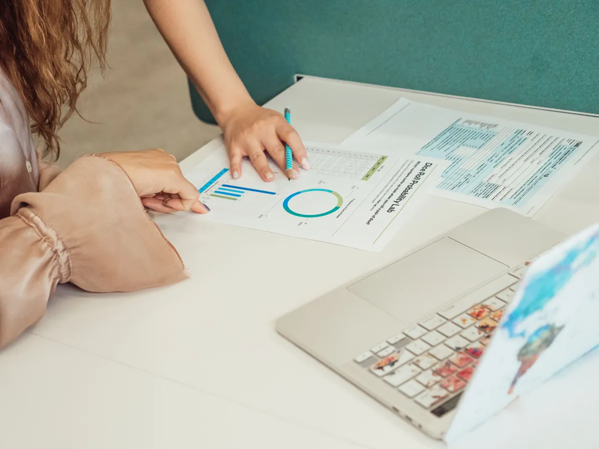 Image of two people looking at printed charts and a laptop