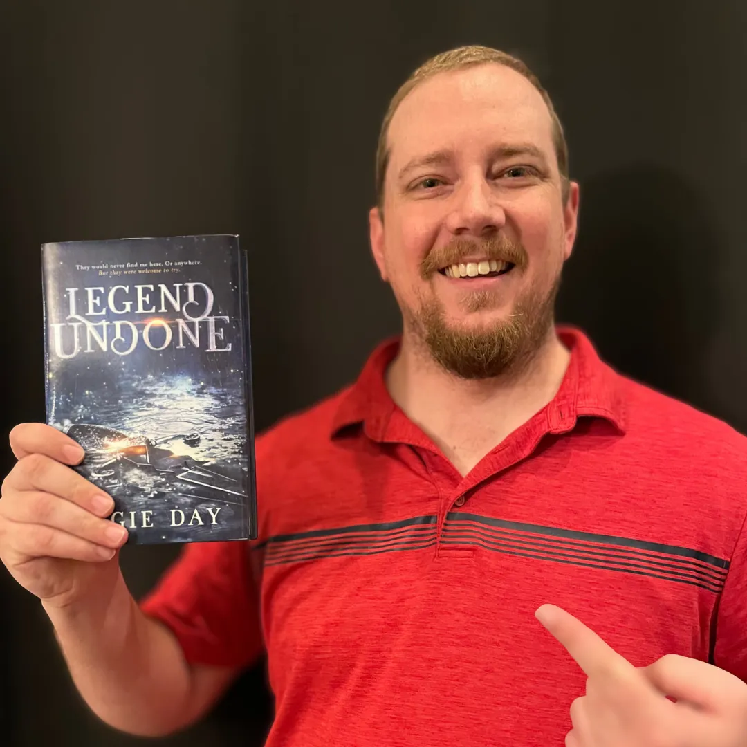 Reader pointing at Legend Undone clean fantasy romance paperback by Angie Day