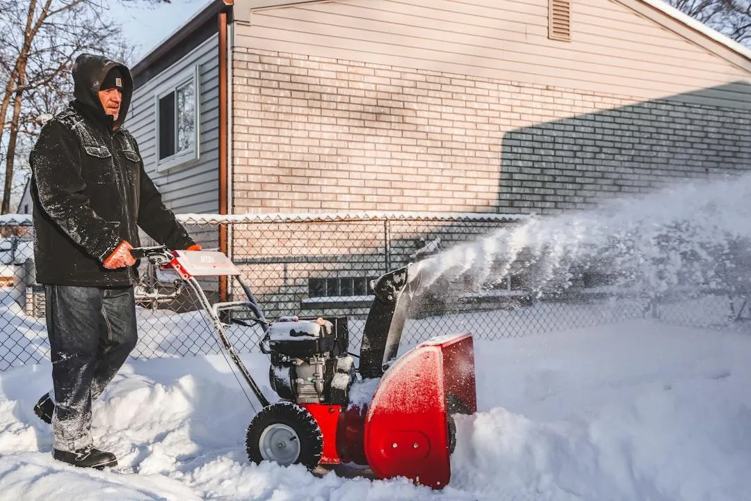 Residential snow removal using a walk-behind snow blower clearing a driveway after heavy snowfall.