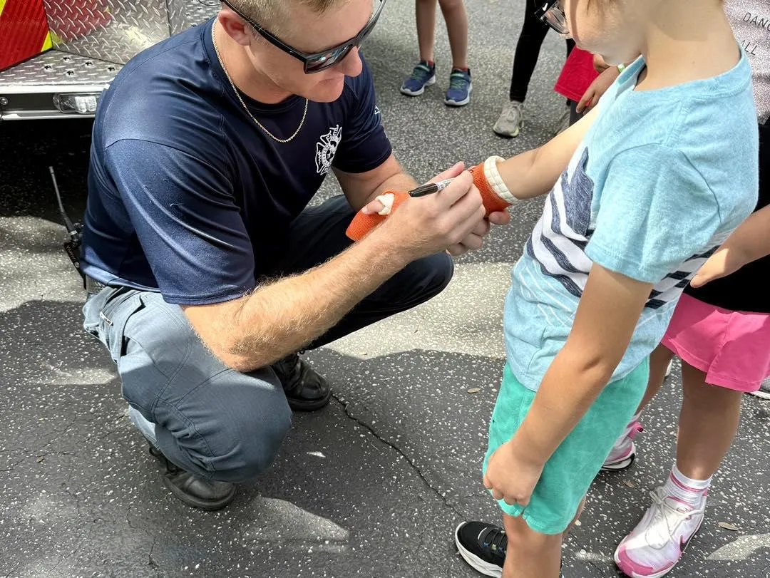 Pasco County Professional Firefighter signing a child's cast during a community outreach event to build trust and support in local neighborhoods