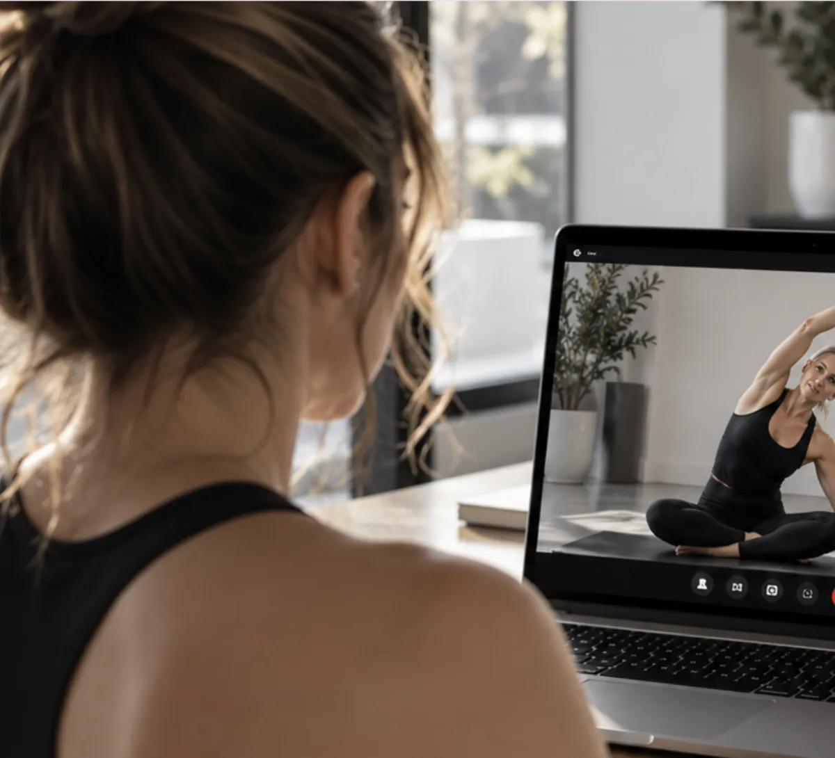 Trainee following a live one-on-one virtual Pilates session on a laptop