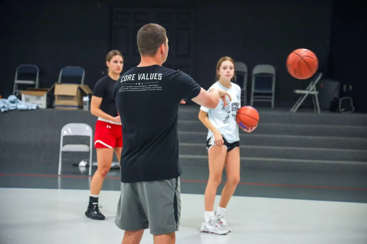 Casey Teson coaching players during a team basketball training session focused on passing and communication