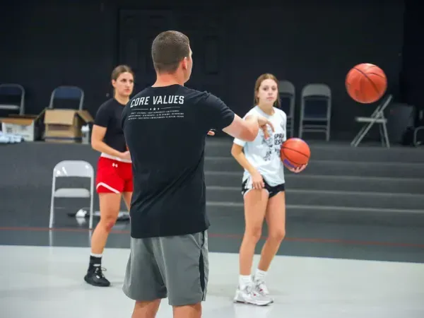 Coach teaching basketball fundamentals to young players in the gym.