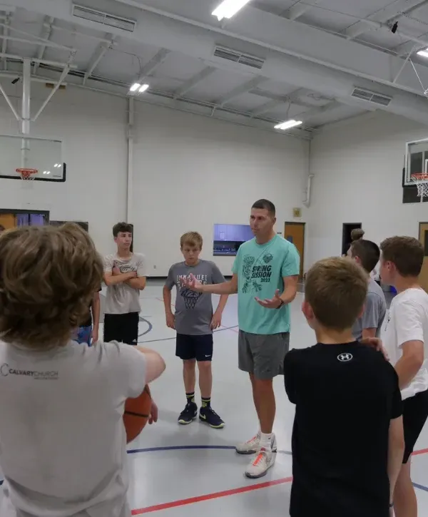 Basketball coach giving instructions to a group of young players during practice. 