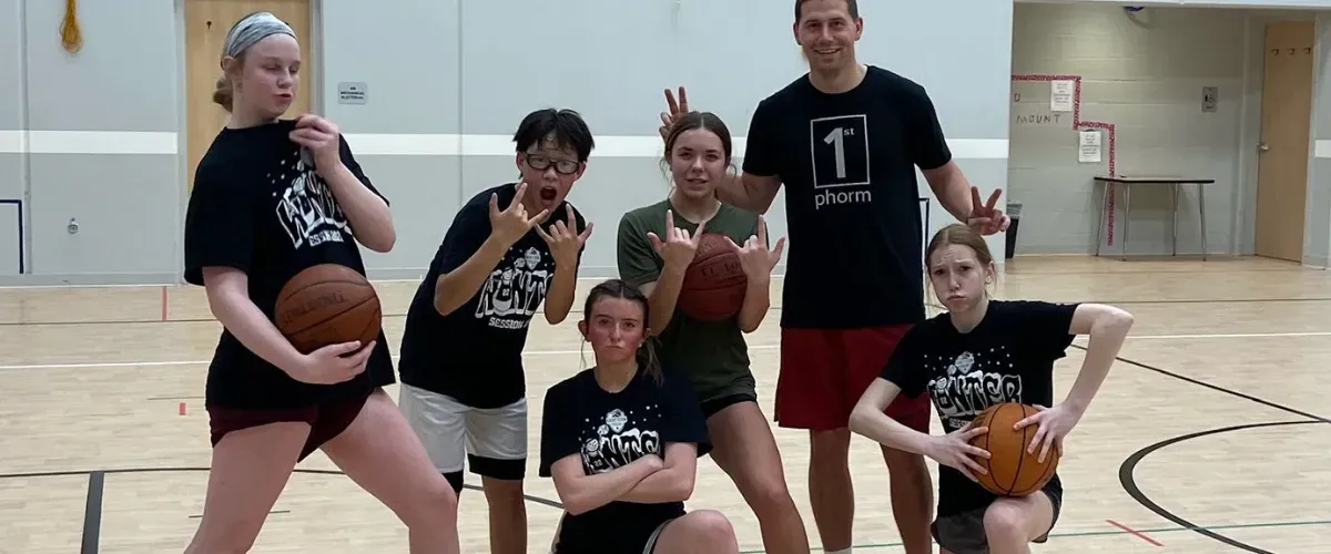 Basketball coach guiding a young player during a one-on-one training session in the gym.
