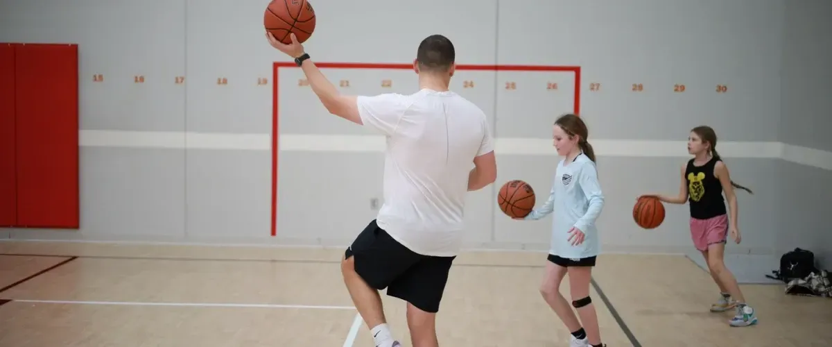 Girls practicing basketball dribbling skills during a youth training camp