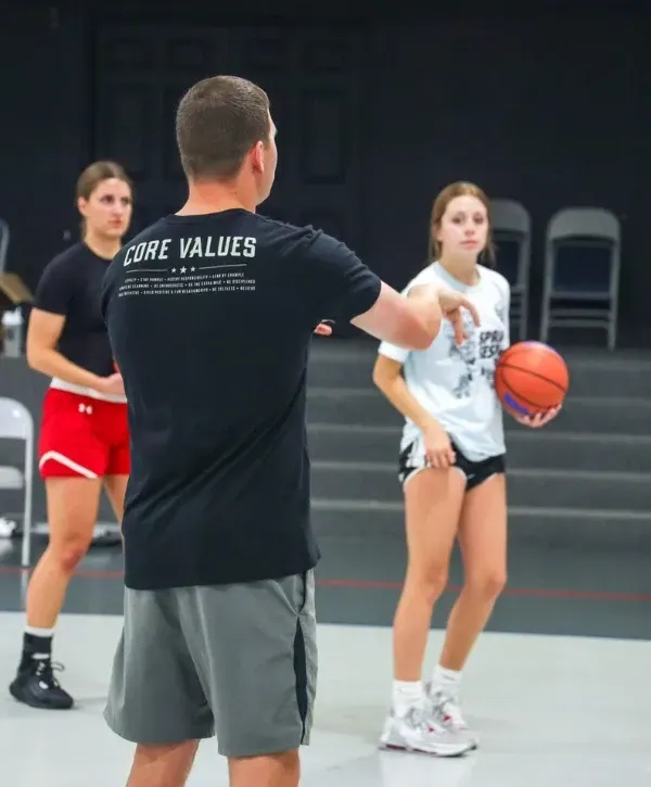 Coach giving instructions to youth basketball players during a practice session.