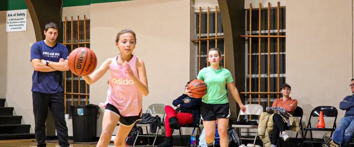 Girls basketball players running an attacking drill in indoor gym