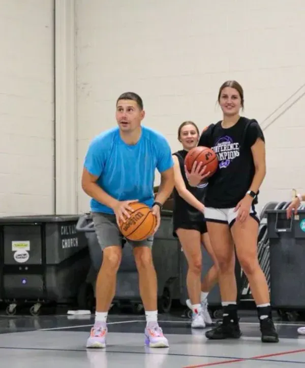 Basketball coach demonstrating free throw technique to young athletes