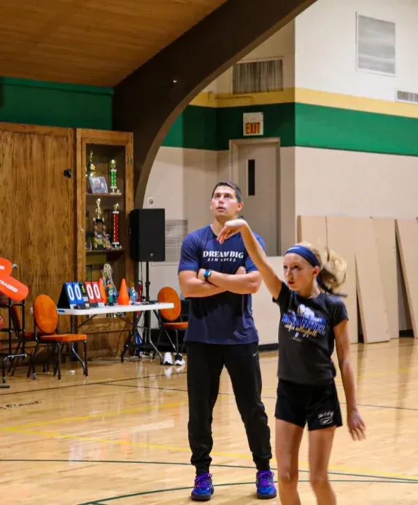 Basketball coach observing and instructing young player during practice