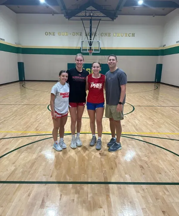 Family standing together on a basketball court inside a gymnasium.
