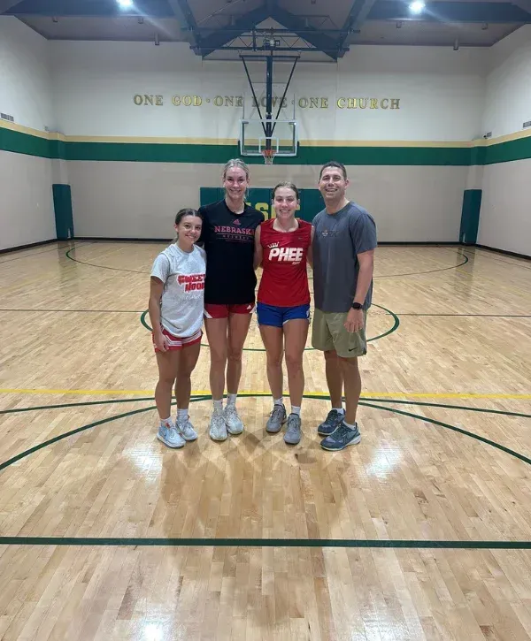 Group photo of youth basketball players and coach on gym court.