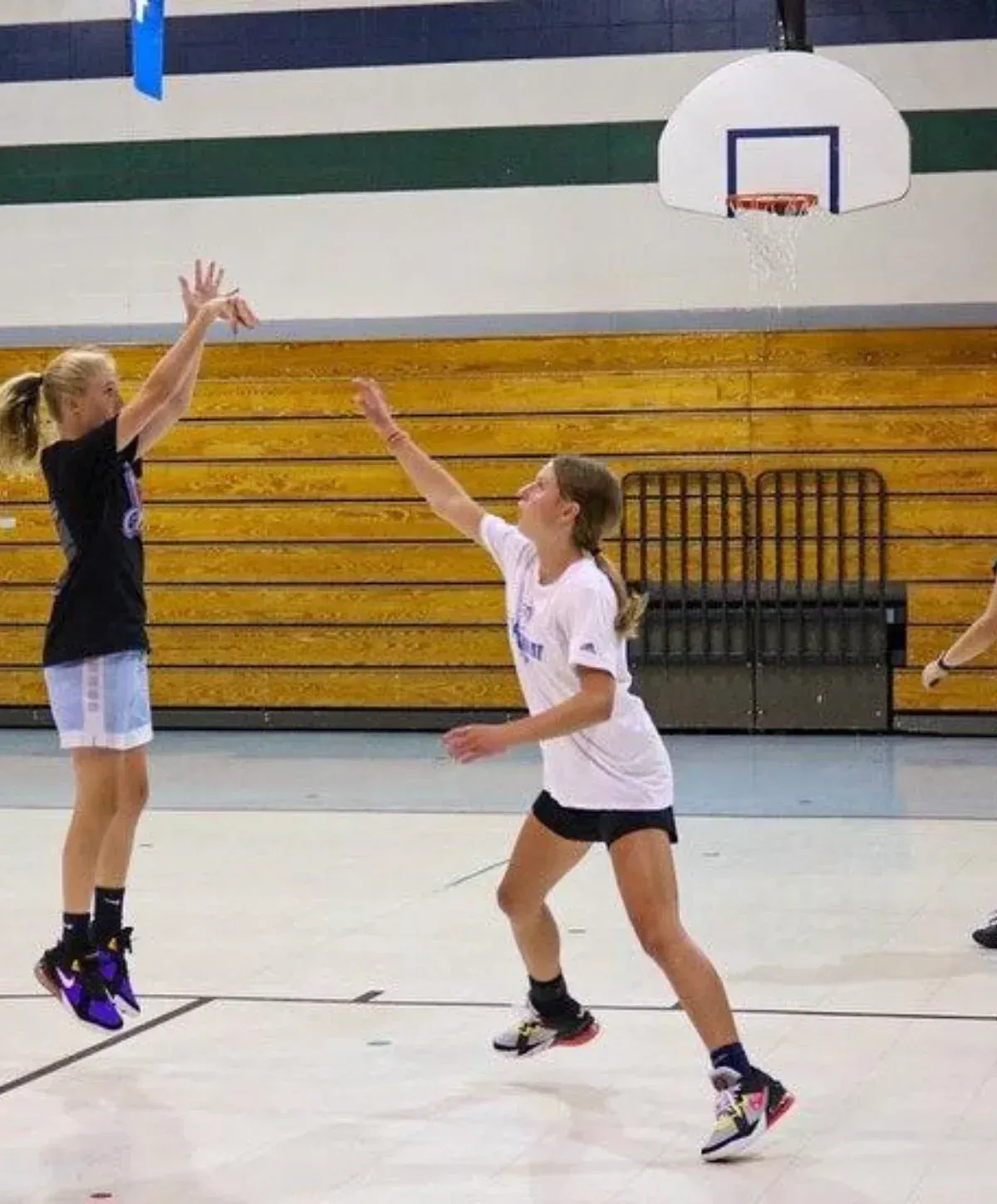 Two individuals, one in a 'USA' shirt and another holding a basketball, stand on a hardwood court.