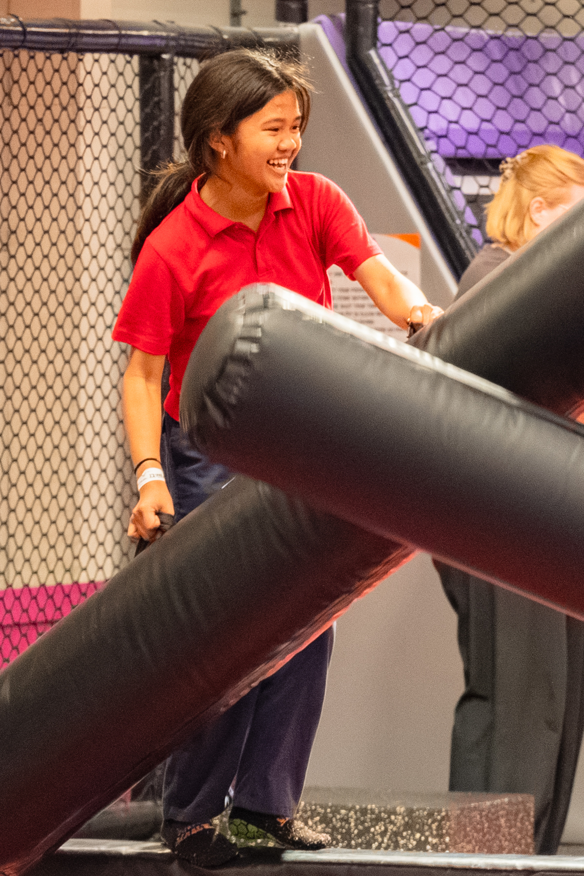 A large school assembly in a bright gymnasium, with students and teachers enthusiastically participating in a group wellness activity. The atmosphere is energetic and supportive, with banners and colorful mats adding vibrancy to the scene.
