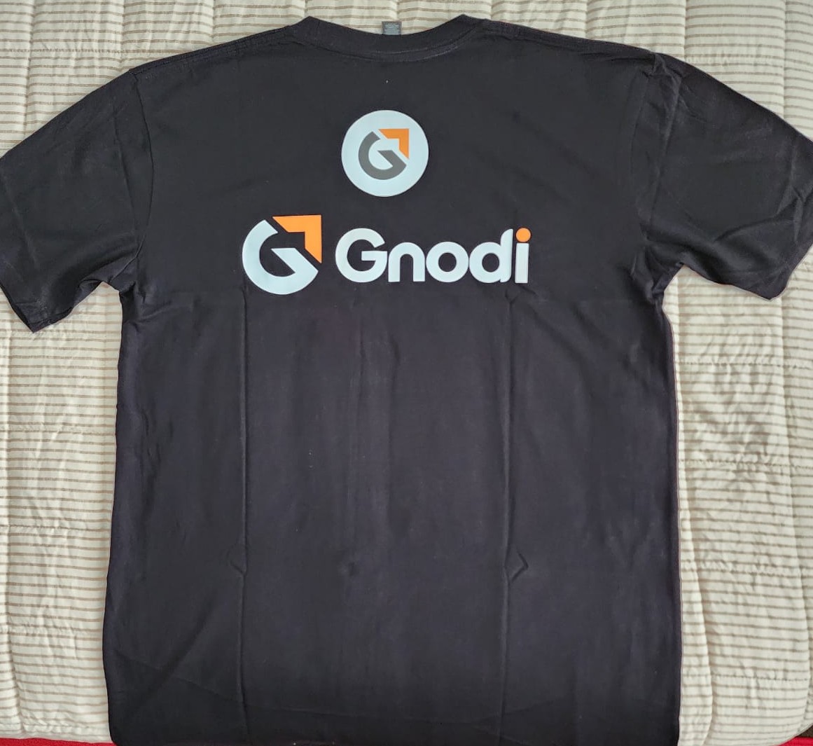 A flat lay of a GNODI WEAR oversized graphic tee with abstract patterns, styled with chunky sneakers and a minimalist watch on a light grey background. 1:1 aspect ratio.