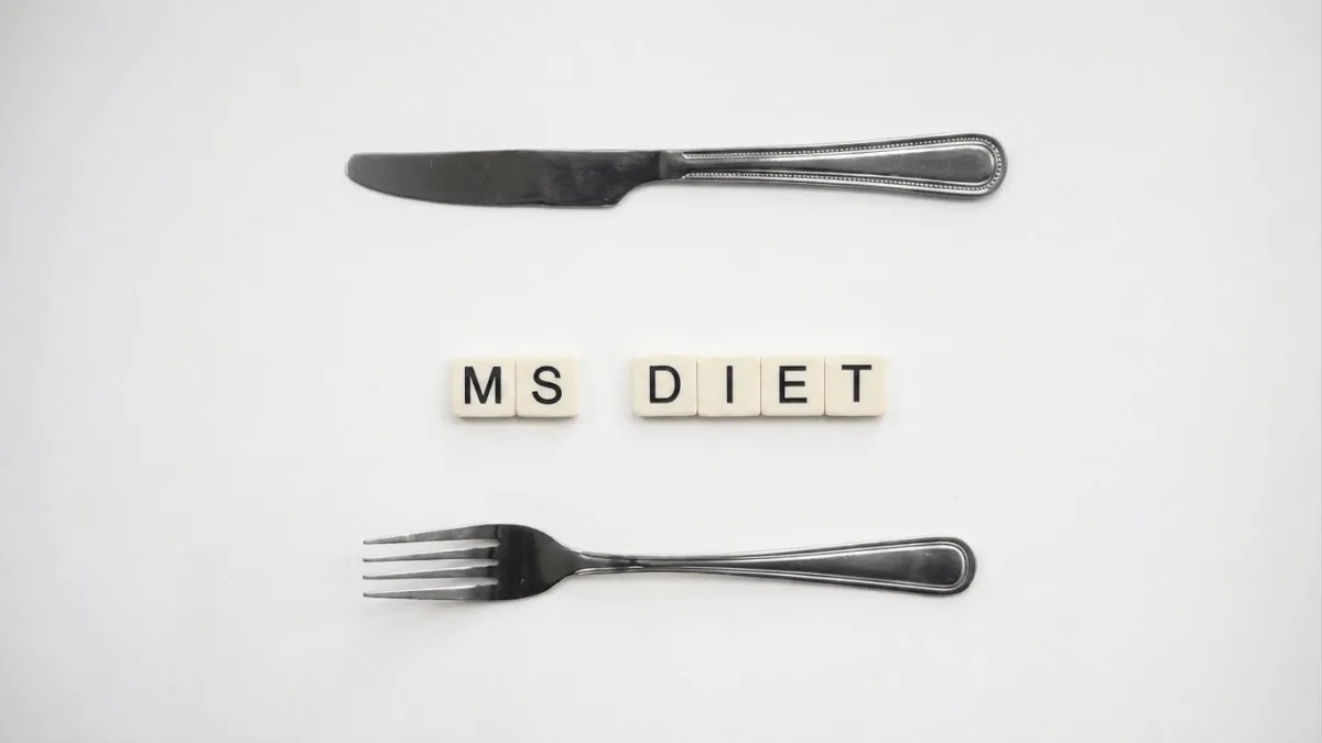Knife and fork arranged around Scrabble-style tiles spelling 'MS DIET,' representing nutrition choices for managing multiple sclerosis.