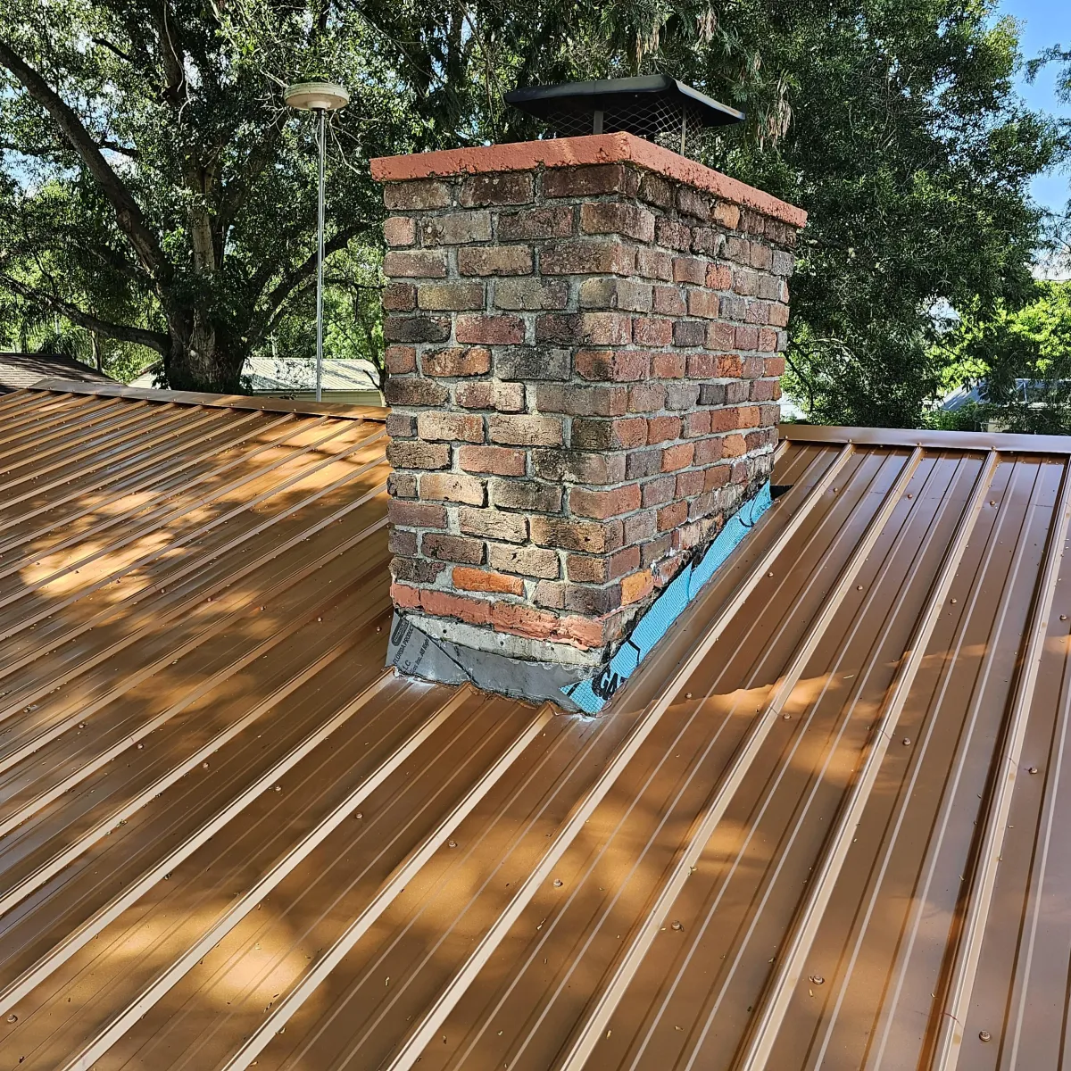 Brick chimney on a metal roof with new step flashing and counter-flashing.
