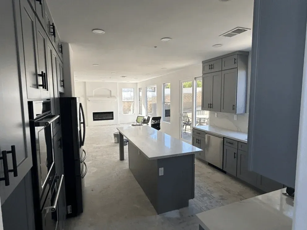 Renovated kitchen in Mentone CA with modern cabinetry, stainless steel appliances, and polished marble island.