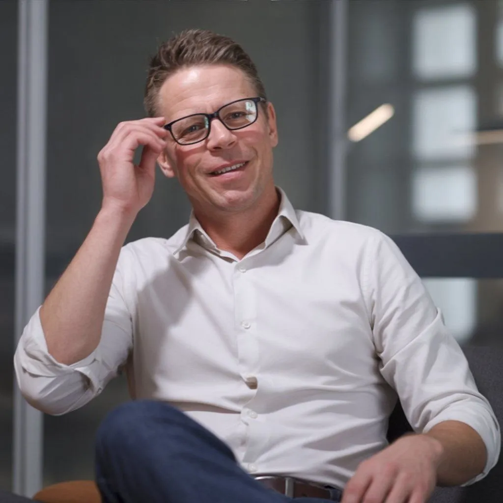 Justin Loughlin, Burnout Coach for high achievers, smiling warmly in a relaxed setting