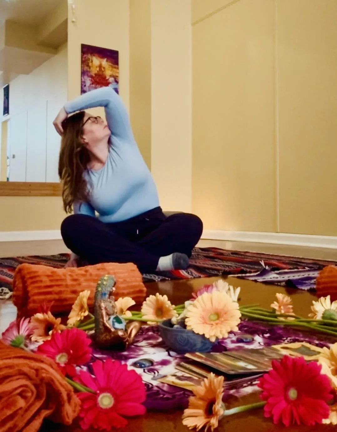 A woman meditating in a sunlit room, surrounded by plants and crystals, exuding calm and focus. She sits cross-legged on a woven mat, eyes closed, hands resting on her knees, with soft morning light streaming through sheer curtains, creating a peaceful, restorative atmosphere.