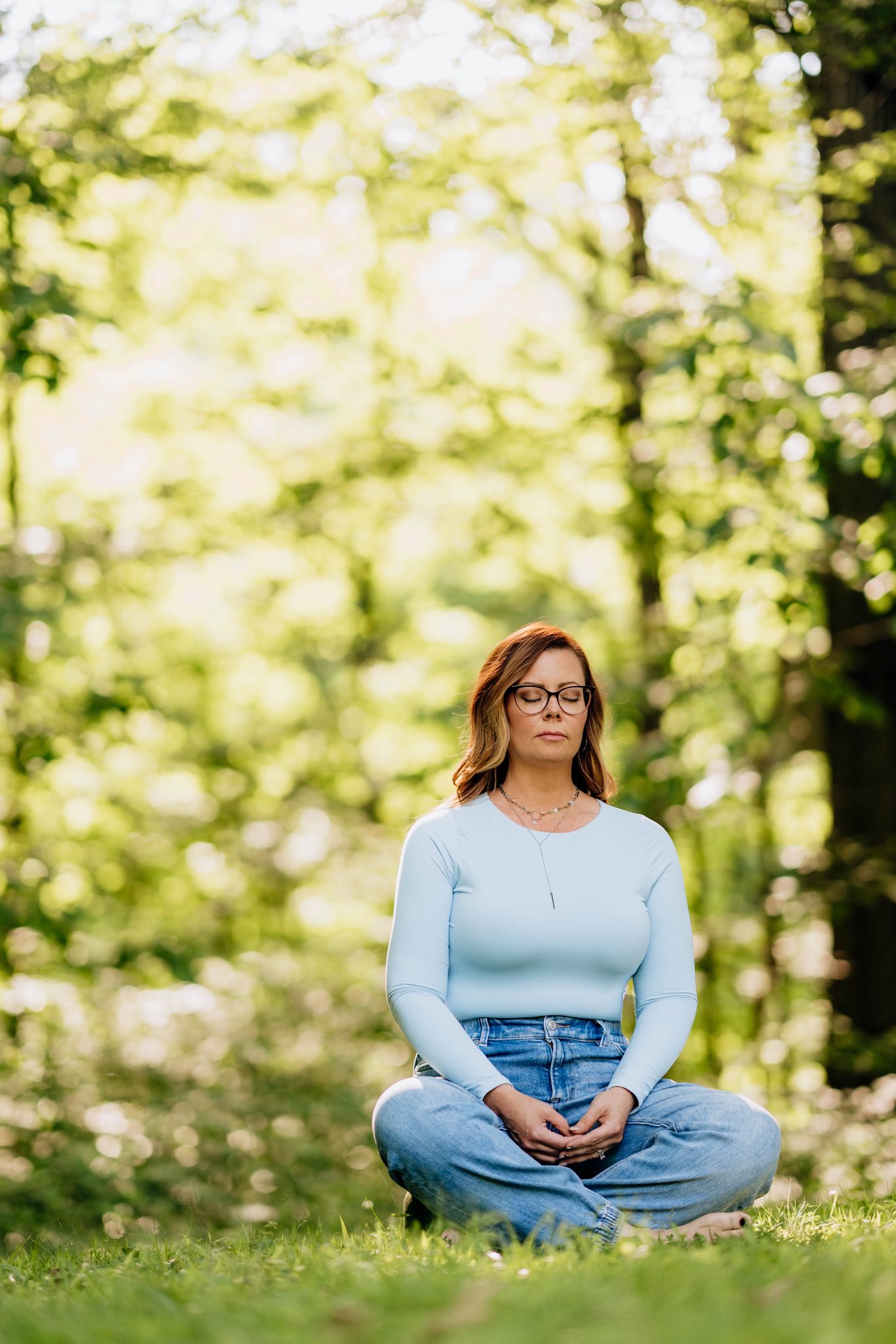 A woman meditating in a sunlit room, surrounded by plants and crystals, exuding calm and focus. She sits cross-legged on a woven mat, eyes closed, hands resting on her knees, with soft morning light streaming through sheer curtains, creating a peaceful, restorative atmosphere.