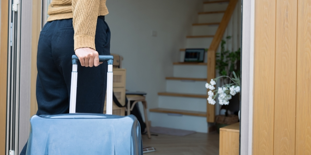Woman with luggage entering home