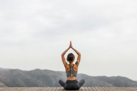 Person practicing yoga meditation outdoors on mountaintop, restoring balance and energy — holistic herbal care for natural healing and wellness support