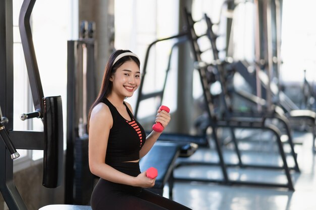 smiling woman lifting weights in the gym, feeling strong and healthy with support from an acupuncture clinic in cupertino, ca.