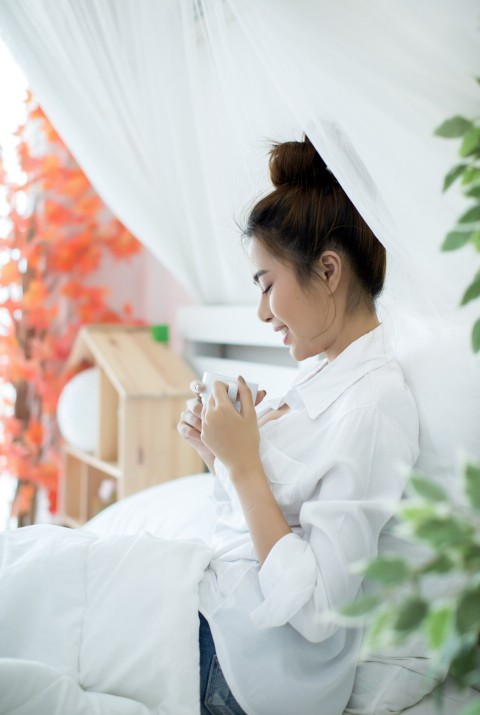 woman in bed enjoying a relaxing morning with a cup of tea after receiving treatment from a herbal medicine practitioner in cupertino ca.
