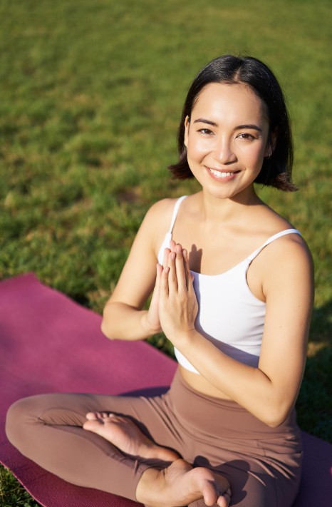 smiling woman sitting in yoga pose outdoors after working with holistic medicine practitioner in cupertino ca.