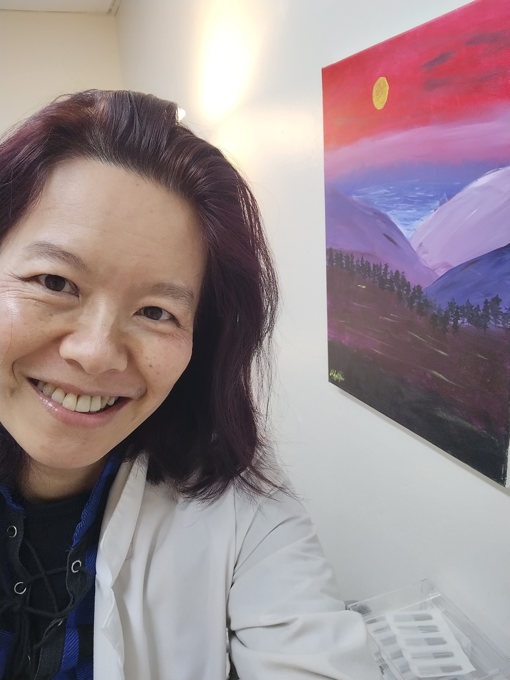 smiling womens health acupuncture provider in cupertino ca standing in a bright treatment room.