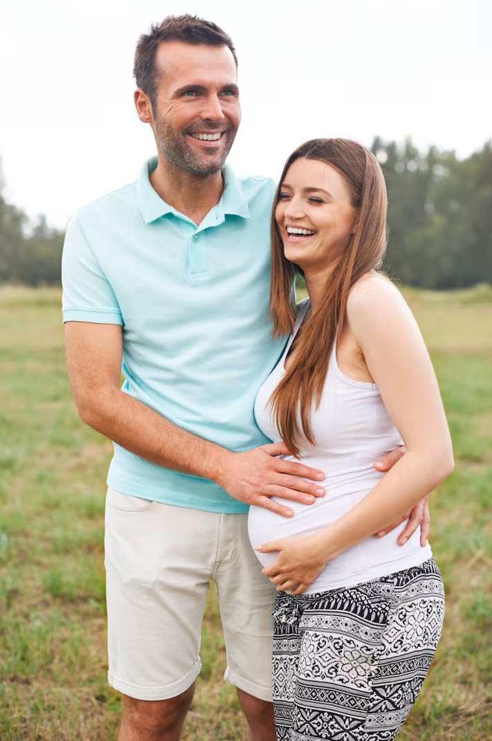 happy pregnant couple smiling outdoors after visiting acupuncture clinic in cupertino ca for fertility support.