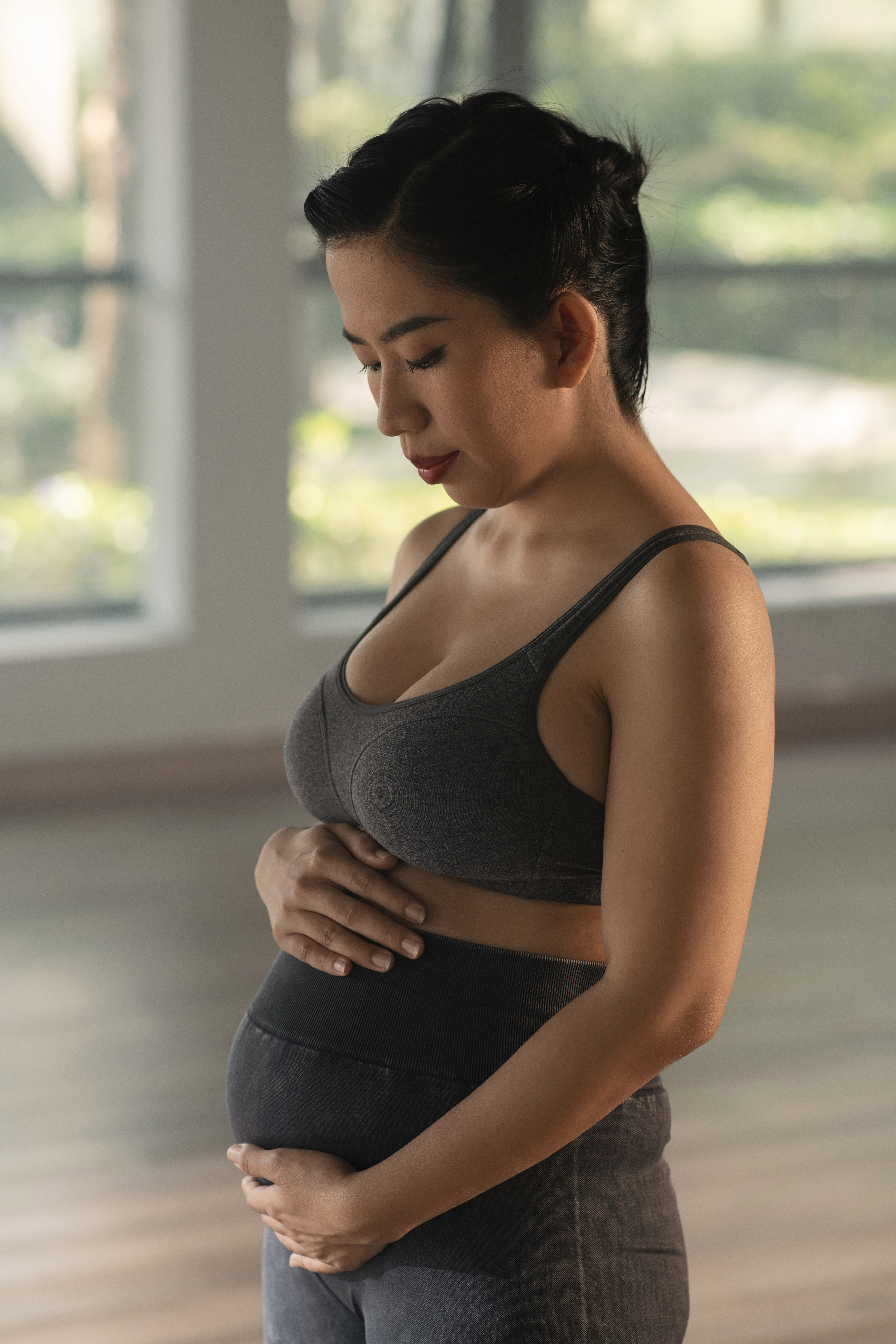 woman holding belly while practicing natural pregnancy support in cupertino ca to focus on her health.