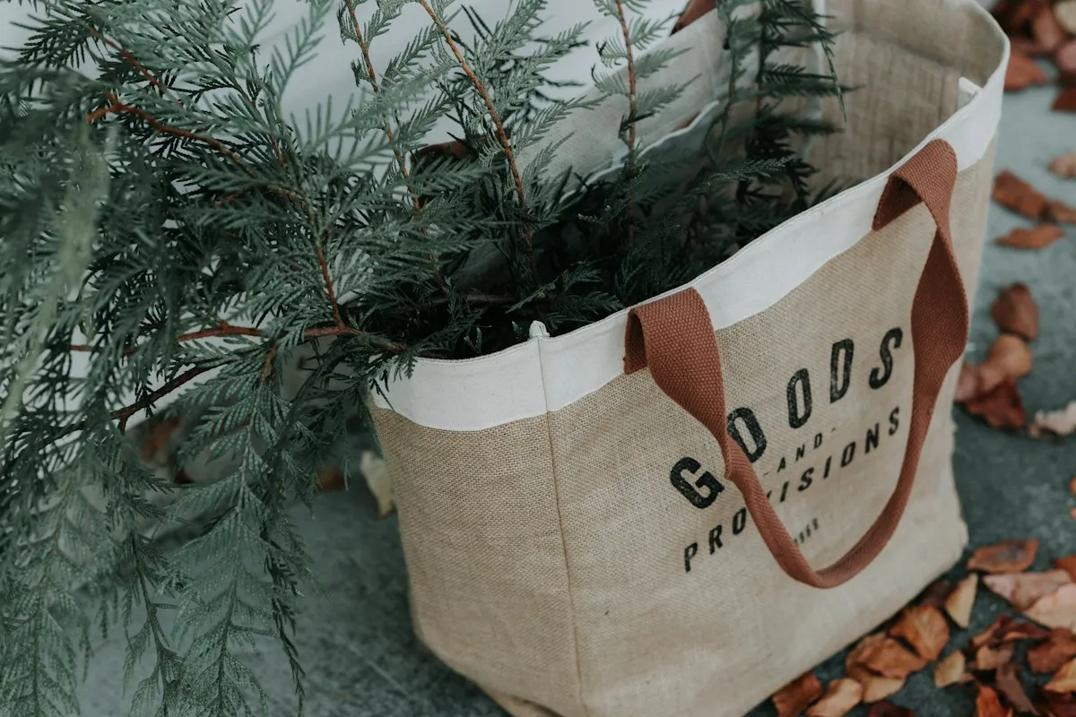 Burlap shopping tote filled with evergreen branches on a fall sidewalk