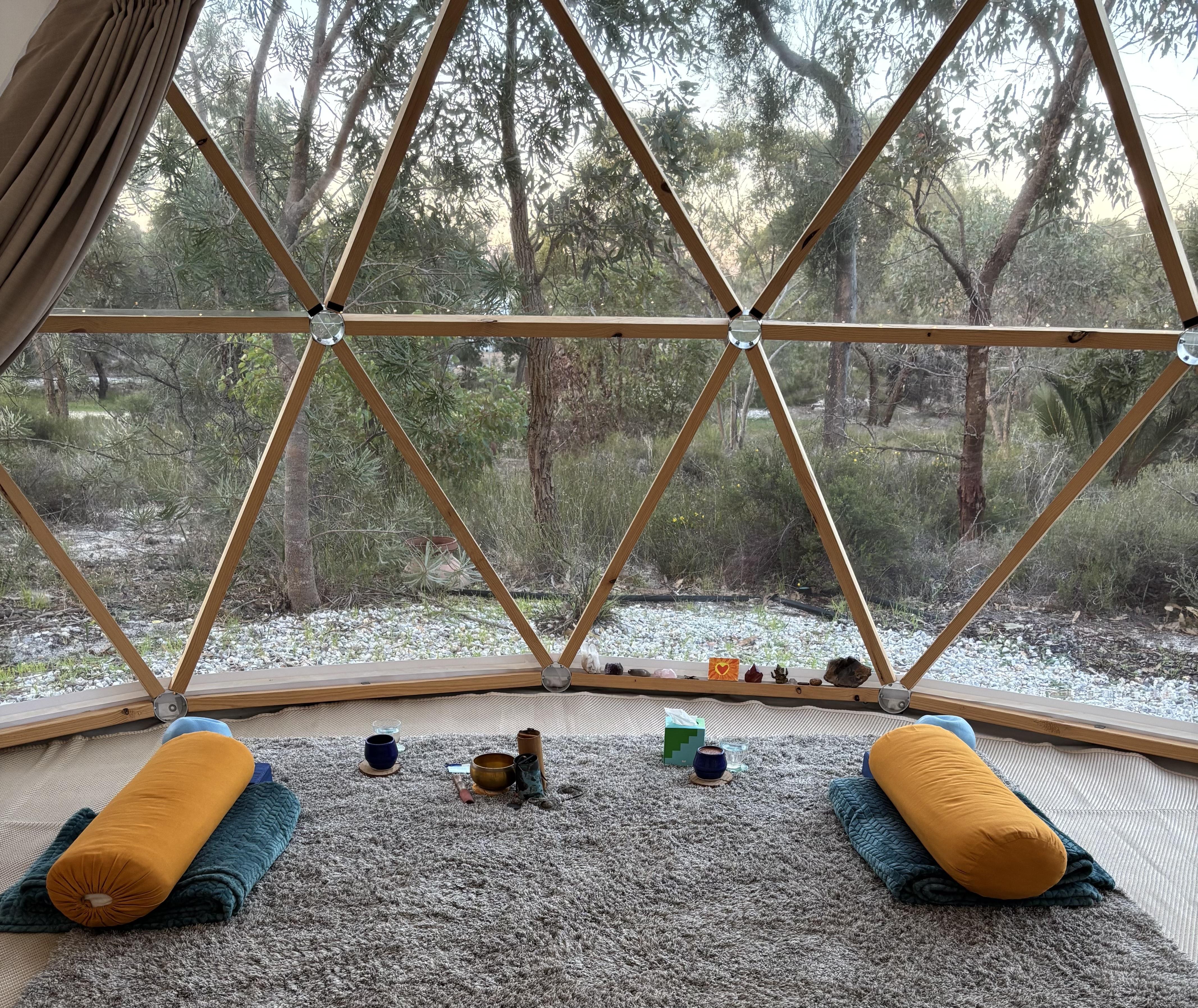 Exterior view of a canvas bell tent nestled among trees in a natural setting