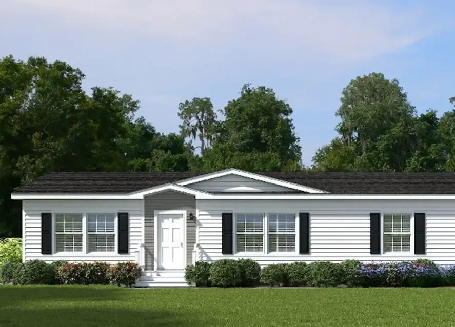 A white single-story Houston Brantley Manufactured Housing unit with black shutters, a black roof, and a white front door. The home is surrounded by green trees and features a well-kept lawn and shrubs in the front.