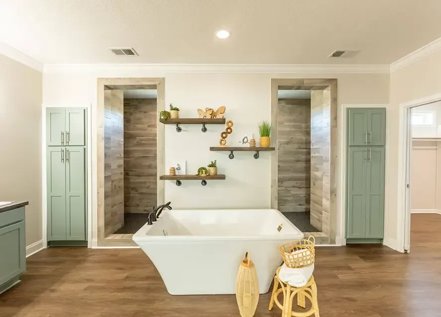 A modern bathroom features a white freestanding bathtub, wood flooring, two tall cabinets, and recessed areas with wooden shelves and decor items.