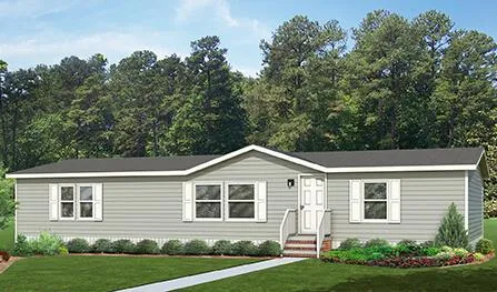 A single-story gray mobile home with white trim and a front porch, surrounded by a green lawn and plants, with a forested area in the background, offered by J Houston Properties Manufactured Homes.