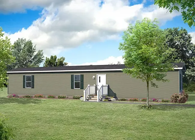 A single-wide manufactured home with a light beige exterior, white doors, and a front porch, surrounded by a well-maintained lawn, with trees and shrubs in the background under a blue sky.