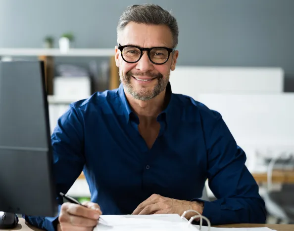 Office worker siting at his desk smiling