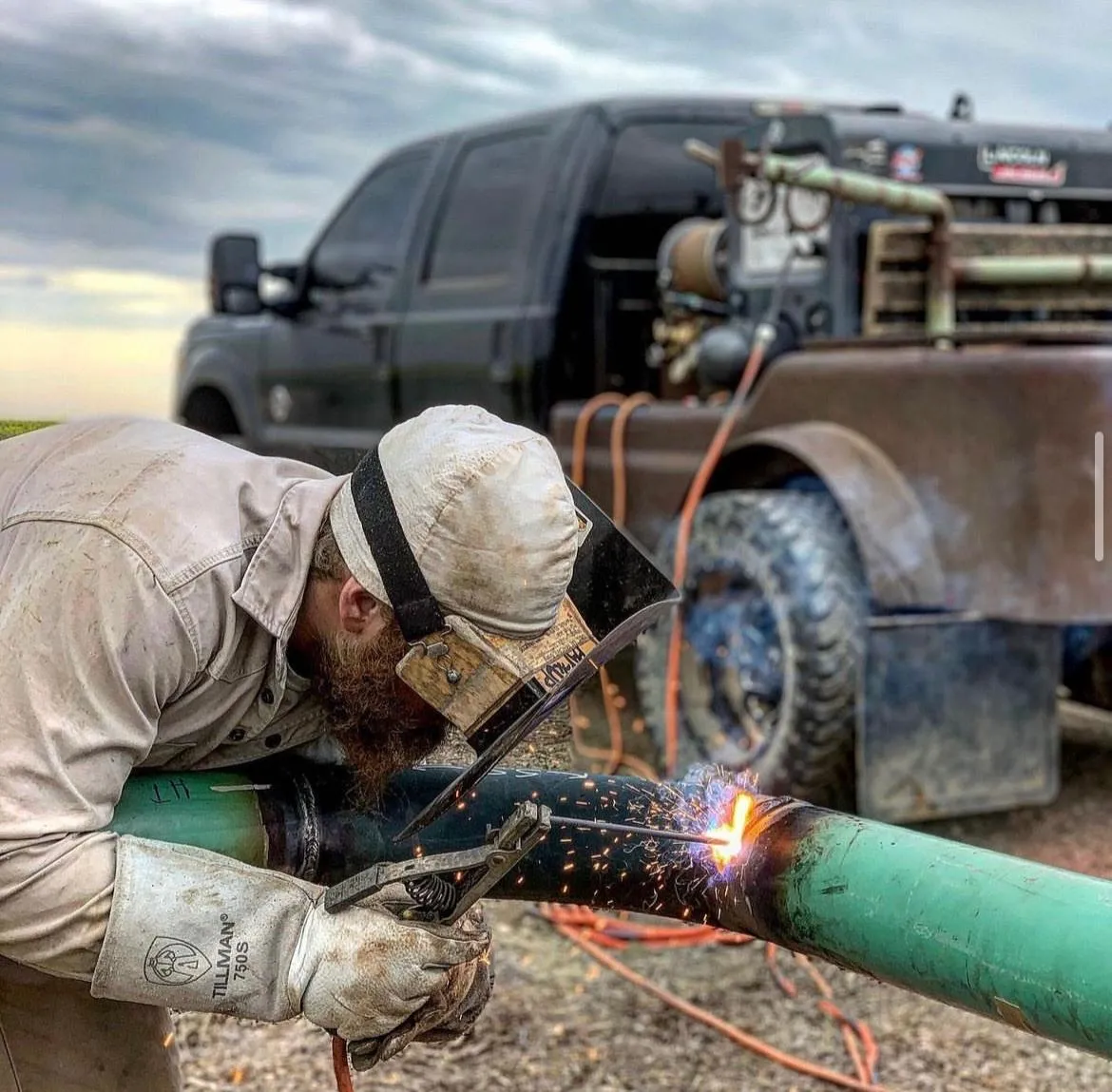 Mobile welding truck at a construction site with technician and steel beams.