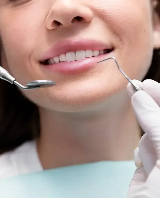 Close-up of a patient smiling during a dental examination with a dental mirror and instrument.