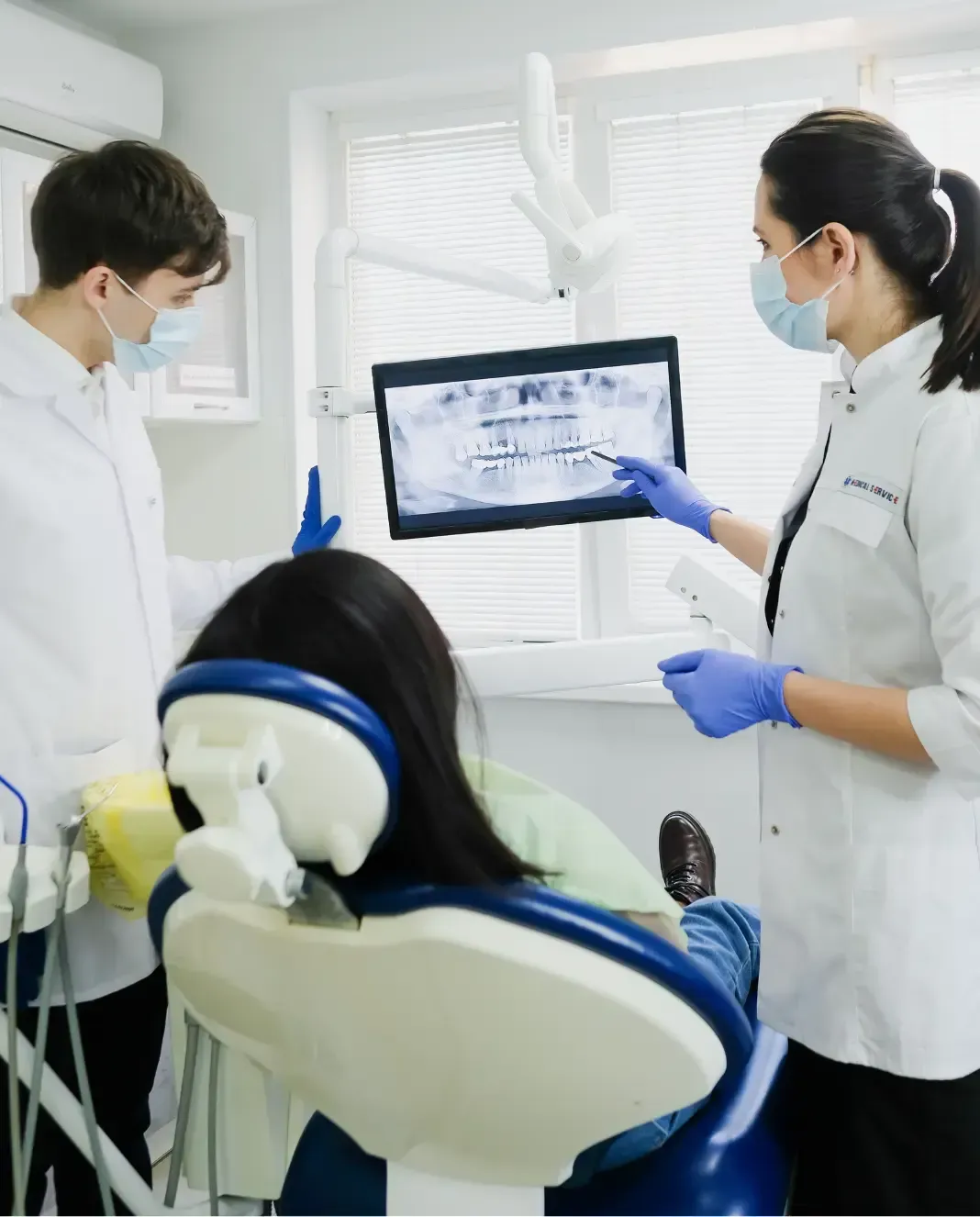 Dental professionals reviewing a patient's digital dental scan while the patient sits in a treatment chair.