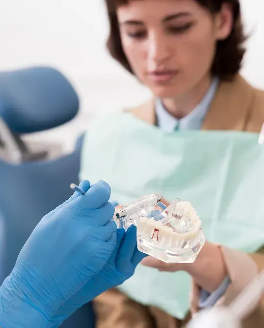 Dental professional holding a clear aligner model while explaining orthodontic treatment to a patient.